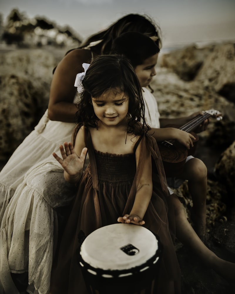 Family Photographer, two happy girls play instruments at the beach with her mom